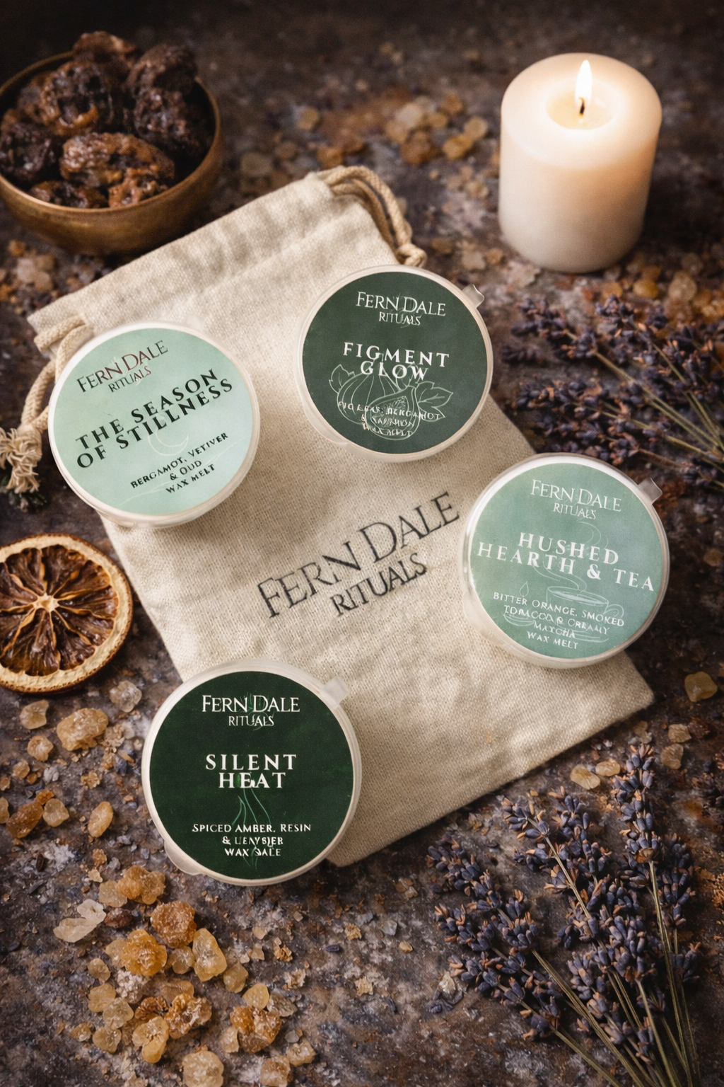 Season of Stillness Wax Melt Collection with four green-labelled pots on a drawstring bag beside a lit candle.